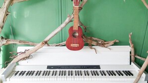 A piano with a red ukulele hanging from a branch. - Forest Cottage Kesennuma (Kesennuma)