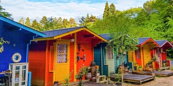 Cabañas coloridas con un diseño rústico, rodeadas de follaje.