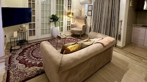 A living room with a beige sofa, a patterned rug, a potted plant, and a flat-screen TV. - EXTACODE APARTMENT (Abuja)