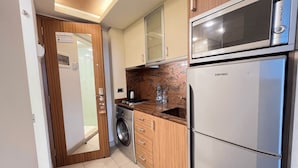 A compact kitchen with a washing machine, a microwave, and a refrigerator. - Digit nomad by List buddy (Jounieh)