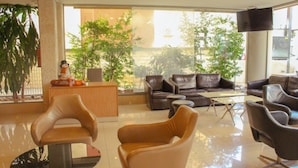 A modern lobby with leather sofas, a reception desk, and a large window offering a view of greenery and buildings. - Digit nomad by List buddy (Jounieh)