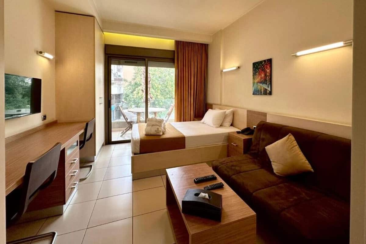 A hotel room with a bed, a sofa, a desk, and a TV.