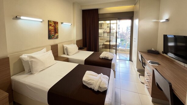 A hotel room with two beds, a desk with a television, and a view of the outdoors through a glass door. - Digit nomad by List buddy (Jounieh)