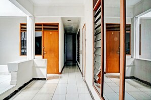 A corridor with wooden doors and a tiled floor. - SPOT ON 93475 Garuda Homestay Syariah (Sukabumi)