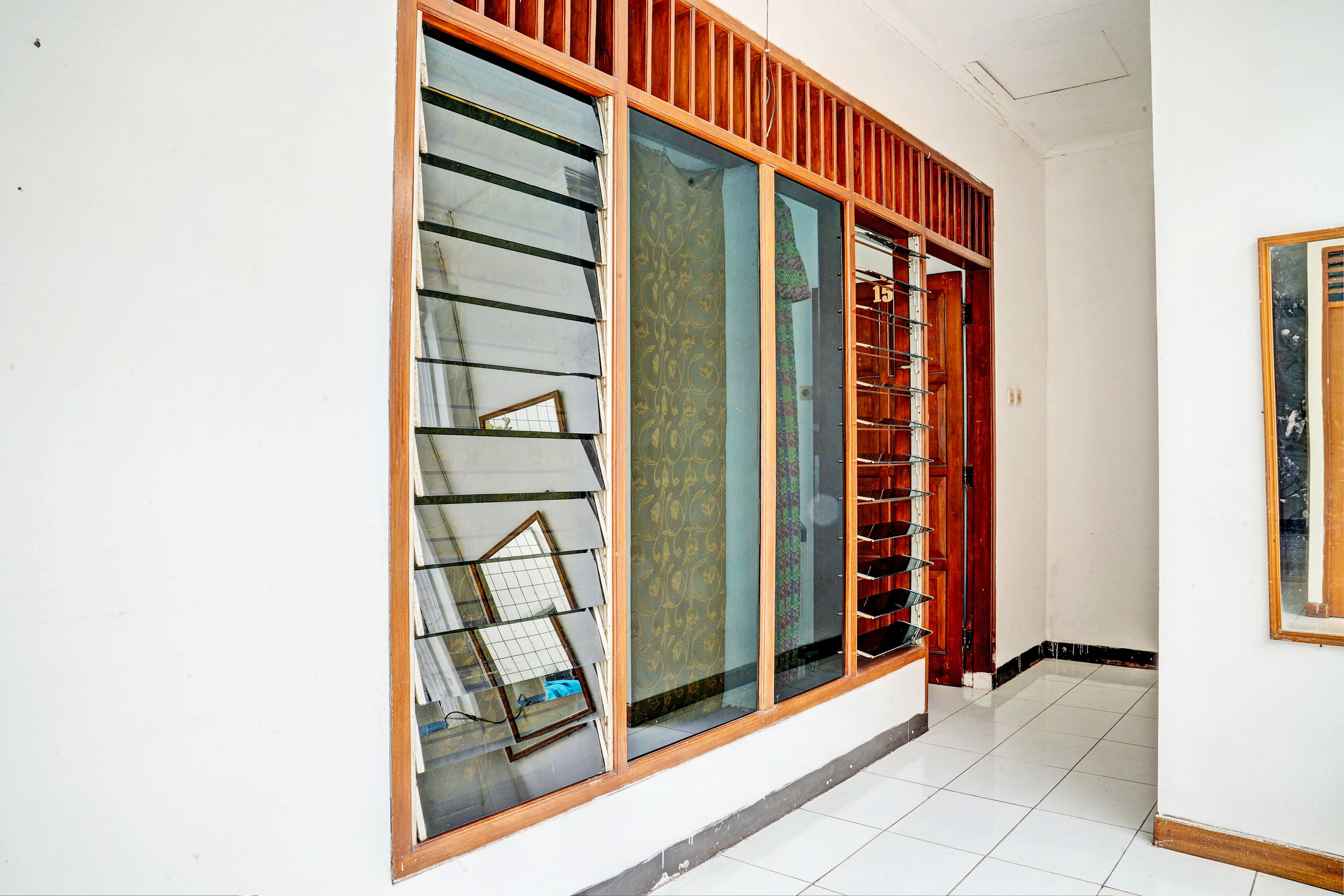 A hallway with a large sliding glass door with a wooden frame, a metal rack with glassware, and a door with a metal handle.