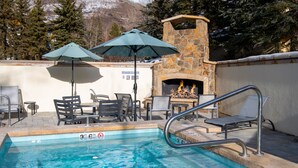 A swimming pool with a stone fireplace and outdoor seating.