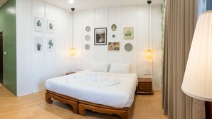 Quarto bem organizado com cama de madeira, roupa de cama branca e diversas obras de arte nas paredes.