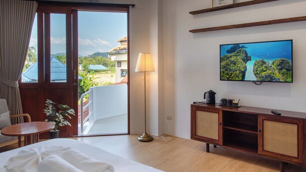 Quarto de hotel com cama, televisão, escrivaninha, luminária e vista para o exterior.