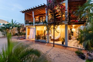 A two-story building with a wooden balcony, a covered outdoor seating area, and potted plants. - Swiss Garten Jeri (Jijoca de Jericoacoara)