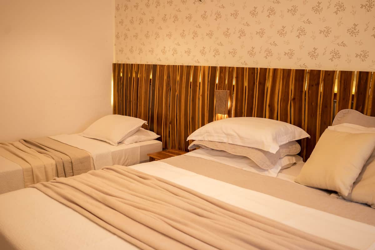 A hotel room with two single beds, a wooden headboard, and a patterned wall.