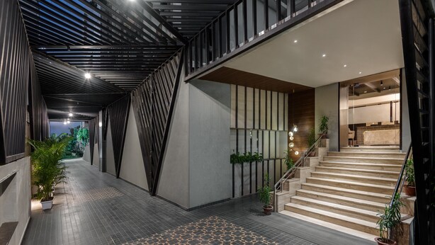 A modern interior with a geometric patterned floor, a staircase, and potted plants. - Voyage Milestone Hotel & Banquet Siliguri (Jalpaiguri)