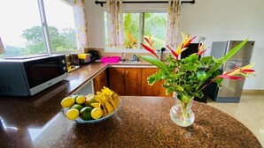 Une cuisine équipée d’un four à micro-ondes, avec un saladier rempli de fruits et un vase de fleurs.