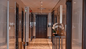 A modern hotel lobby with a marble floor, glass walls, and a wooden door. - SAVOYE HOTEL (Jeddah)