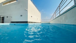 An indoor swimming pool with clear blue water, a white wall, and a metal railing. - SAVOYE HOTEL (Jeddah)