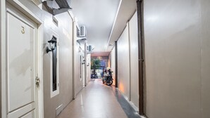 A narrow hallway with a tiled floor, a door with a number plate, and a motorcycle parked at the end. - Hotel O Almahyra Guest House Syariah (Jambi)