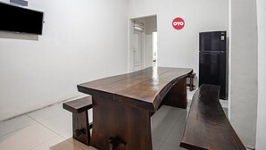 A modern kitchen with a large wooden table, a bench, and a black refrigerator. - Hotel O Almahyra Guest House Syariah (Jambi)