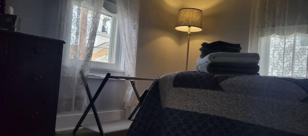 Ett sovrum med en säng, en golvlampa och ett fönster med gardiner.