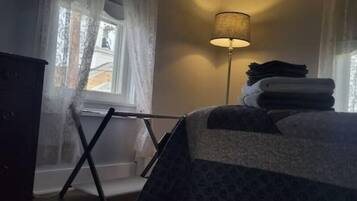 Ett sovrum med en säng, en golvlampa och ett fönster med gardiner.