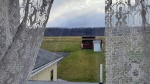 A rural landscape with a small building and a fenced area.