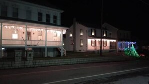 A two-story house with a porch and a Christmas tree decorated with lights.
