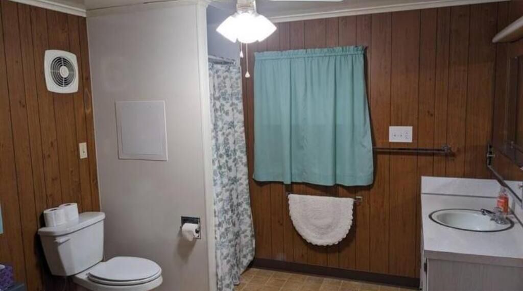 A bathroom with a toilet, a sink, a shower curtain, and a towel rack.