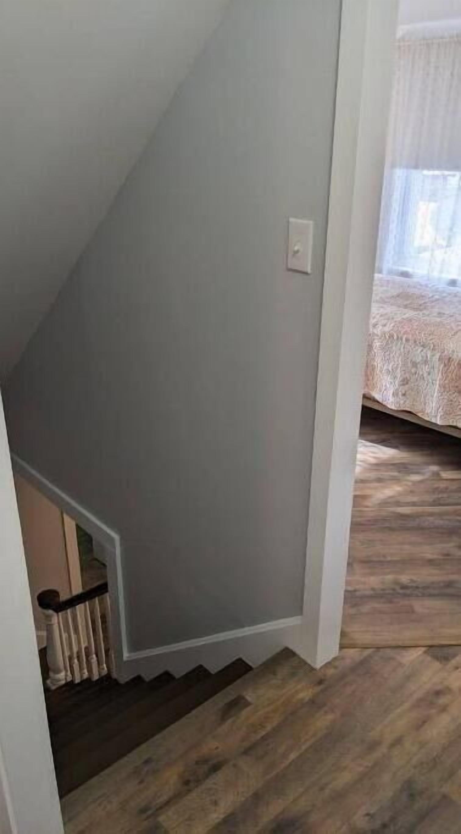 A room with a wooden floor, a grey wall, and a white ceiling.