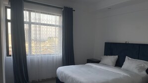 Un dormitorio con una cama grande, una mesita de noche y una ventana con cortinas.