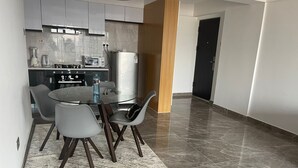Una cocina moderna con zona de comedor, que incluye una mesa redonda de vidrio y sillas grises.