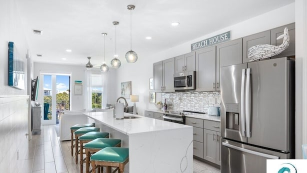 A modern kitchen with a large island, stainless steel appliances, and a view to the outside. - On Beach Time - New Construction - Deeded Beach Access / 3 Pools (Santa Rosa Beach)