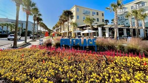 A hotel entrance with a sign reading "CULEBRAS" surrounded by a garden of yellow flowers and palm trees. - On Beach Time - New Construction - Deeded Beach Access / 3 Pools (Santa Rosa Beach)