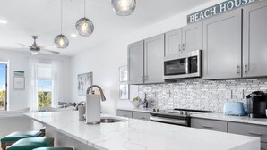 A modern kitchen with grey cabinets, a white countertop, and a sign that reads "BEACH HOUSE". - On Beach Time - New Construction - Deeded Beach Access / 3 Pools (Santa Rosa Beach)