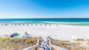 A beach with a wooden walkway leading to the water, a row of beach chairs, and a surfboard. - On Beach Time - New Construction - Deeded Beach Access / 3 Pools (Santa Rosa Beach)