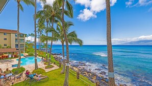 A pool area with lounge chairs, palm trees, and a view of the ocean. - Chic Oceanfront Escape-Boutique Studio-Noelani 219-Cold AC-Amazing Ocean View (Lahaina)