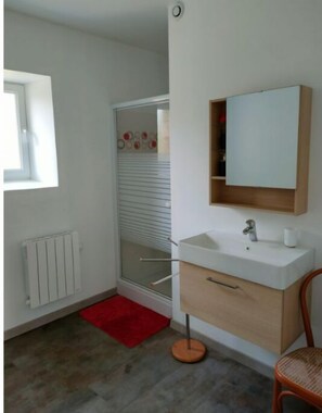 Bathroom features a white sink, mirror, and radiator, with a wooden cabinet and red rug.