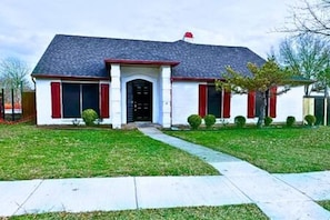 A residential house with a front porch, a driveway, and a well-maintained lawn.