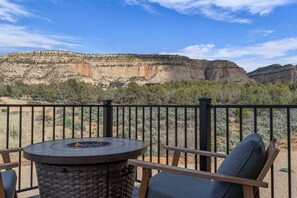 Een terras met een ronde tafel en stoelen, met uitzicht op een bergachtig landschap.