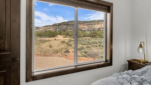 A bedroom with a large window offering a view of a mountainous landscape.