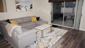 A living room with a grey sectional sofa, a white coffee table, and a patterned rug.