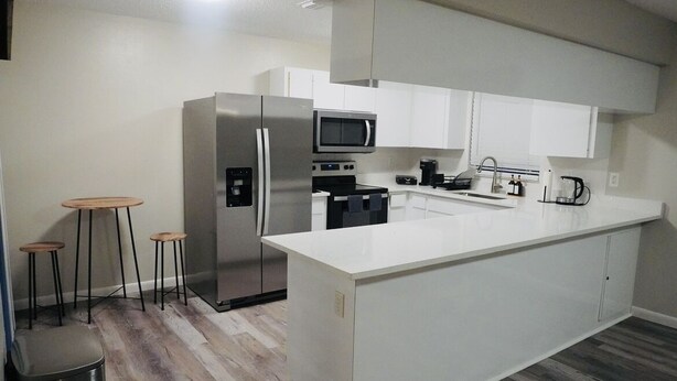 A modern kitchen with white cabinetry, stainless steel appliances, and a central island.