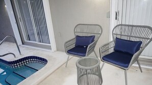 A pool area with two wicker chairs and a small round table.