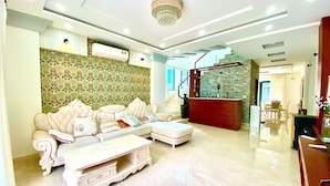 A spacious living room with a large white sofa, a coffee table, and a staircase leading to an upper floor. - Trang Tien Villas (Phu Quoc)