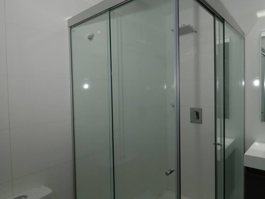 A modern bathroom with a glass-enclosed shower, a white toilet, and a sink.