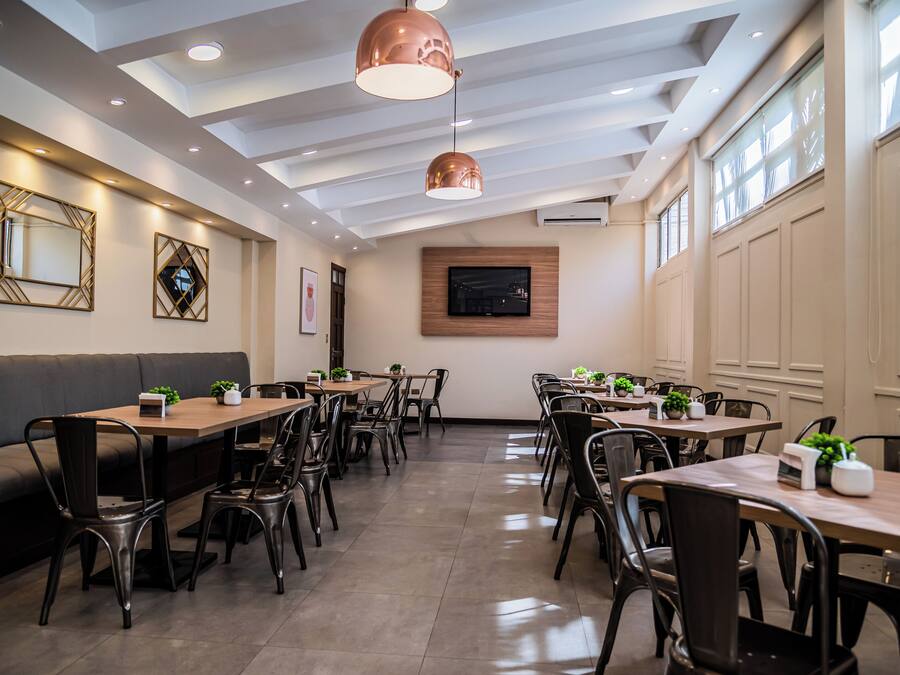 Uma sala de jantar moderna com uma mesa comprida, várias cadeiras e iluminação pendente.