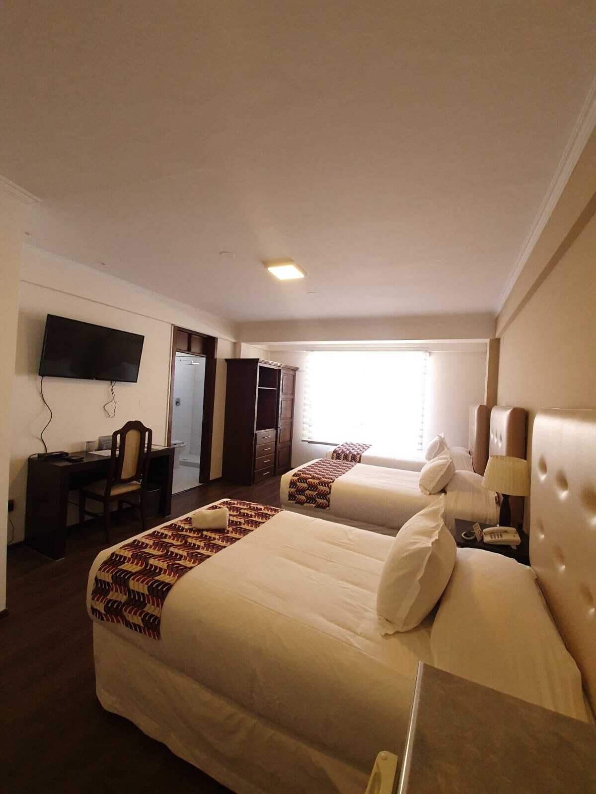 Habitación de hotel con dos camas, un escritorio, un televisor y un armario.