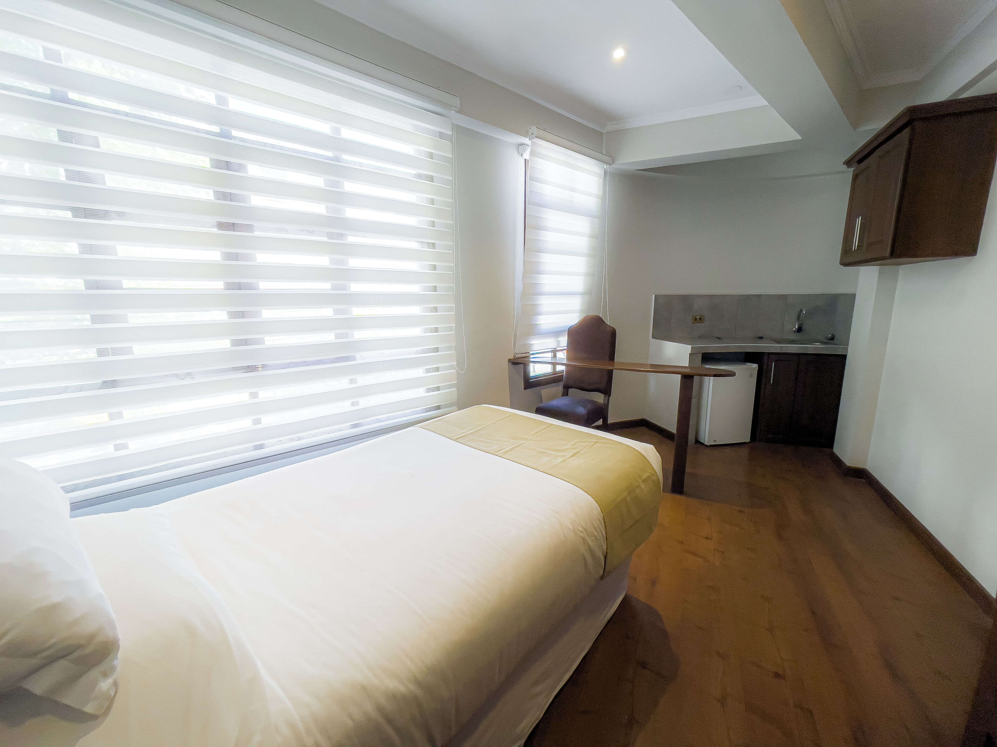 Een hotelkamer met een bed, bureau, stoel en kitchenette.