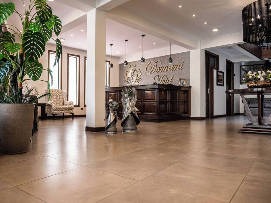 A spacious lobby with a reception desk, large potted plants, and a chandelier.