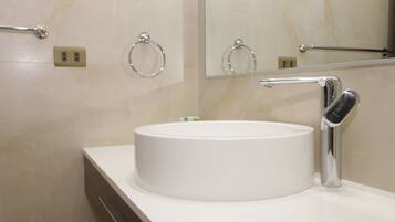 Un baño moderno con un lavabo blanco redondo, grifo cromado y un espejo encima.