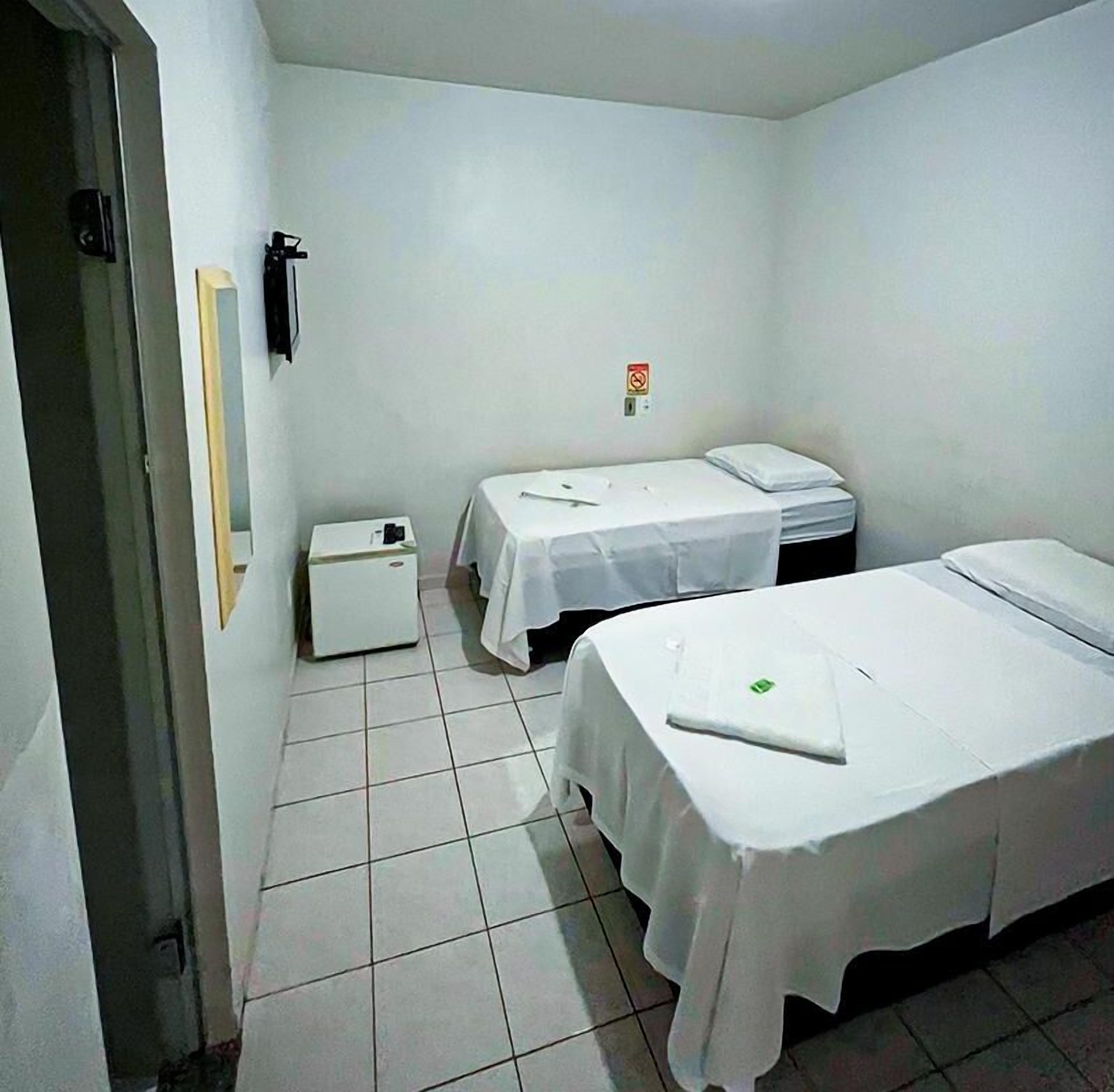 A small, clean room with two single beds, a small heater, and a door.