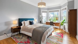Une chambre à coucher avec un lit, des tables de chevet, un bureau et une chaise.