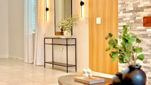 A modern interior with a console table, a mirror, and a vase with a plant. - Luxe Orlando Villa - Game Room, Pool, Resort Amenities Near Disney (Four Corners)